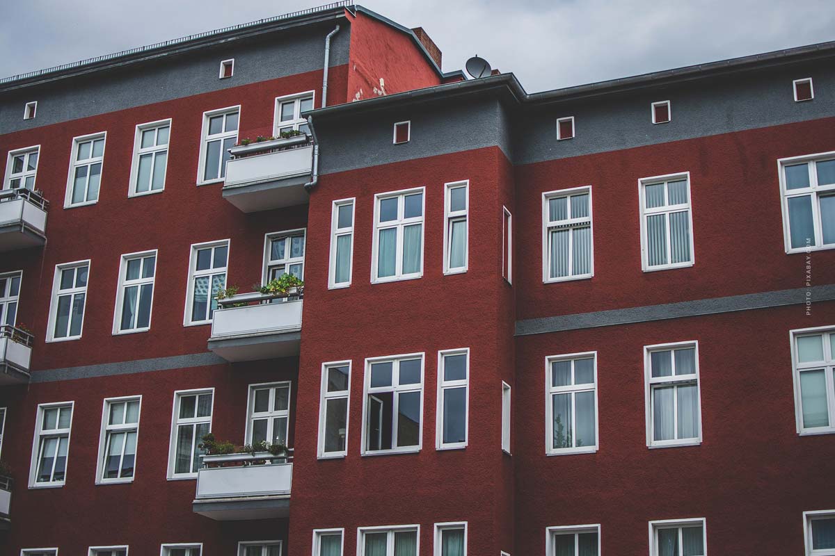 Neubau Mehrfamilienhaus mit roter Fassade, weißen Fenstern und Balkon